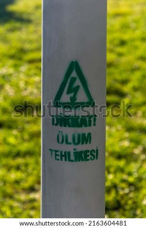 Dispersed paint, Attention! Danger of death (in Turkish Dikkat! Ölüm tehlikesi). Lightning icon indicating possible electric shock.