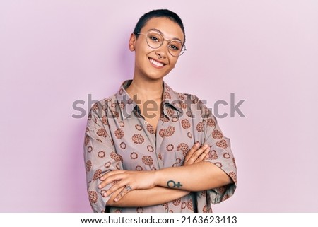 Beautiful hispanic woman with short hair wearing glasses happy face smiling with crossed arms looking at the camera. positive person.  Royalty-Free Stock Photo #2163623413