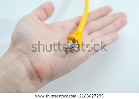 Women's hand holds yellow RJ-45 cable  