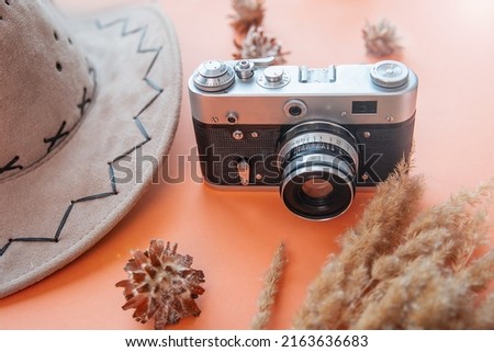 vintage camera on orange background with travel hat. vacation weekend and adventure concept
