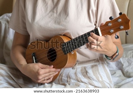 ukulele in women's hands, learning to play the ukulele close-up, Girl playing the ukulele, selective focus. Royalty-Free Stock Photo #2163638903