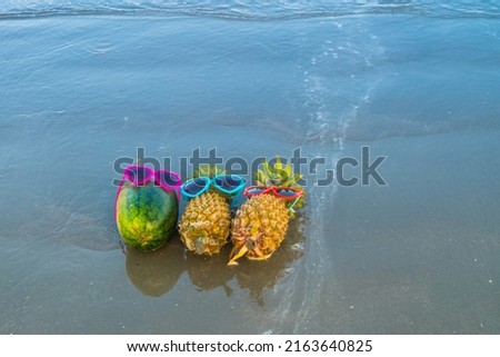 Funny pineapple in stylish sunglasses on a beach.
