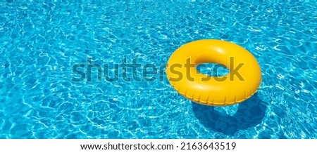 Yellow inflatable ring floating in swimming pool. Vacation concept with copy space Royalty-Free Stock Photo #2163643519