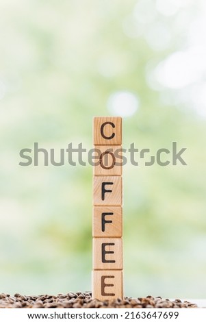 Coffee word is written on wooden cubes on a green summer background Closeup of wooden elements