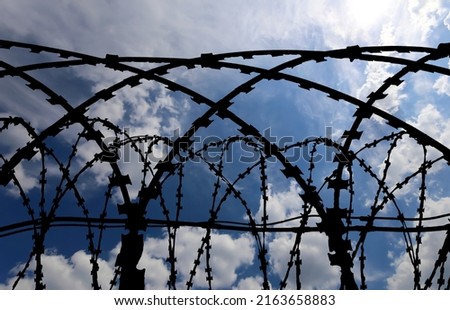 Сontour of barbed wire on background beautiful clouds and sky 