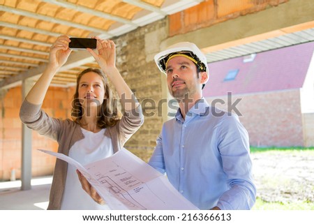Young attractive woman and architect on construction site 