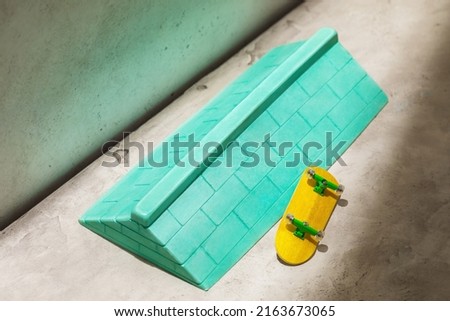 Green plaster ramp with brick wall texture and yellow fingerboard on abstract background