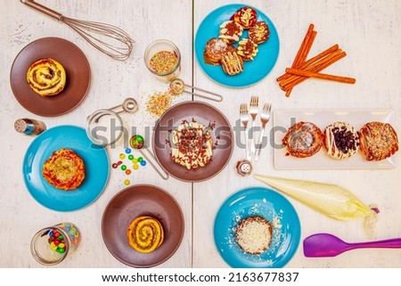 Top image of a set of dessert plates, cinnamon roll, cinnamon stick, chocolate chips and pastry bag