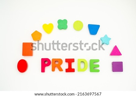 Word pride with rainbow in colored block lettering with colored rainbow shapes in background on white lay flat
