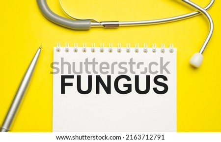 fungus word on notebook and stethoscope on yellow background