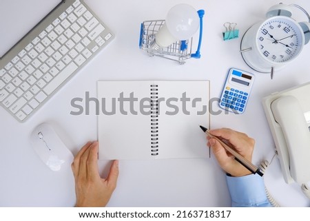 Office desk with smartphone, laptop computer, cup of coffee, and office tools. Flat lay, top view with copy space. A bank notepad and a pen are on top of an office desk table containing computer tools