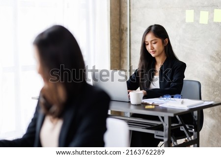 Portrait of Asian office employee businesswoman working in an office, doing planning analyzing the financial report, business plan investment, finance analysis concept. Office background.