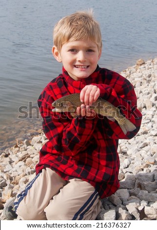 Happy boy and a Rainbow Trout fish caught fly fishing at a lake