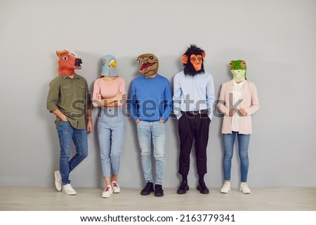 Funny half people half animals waiting by office wall together. Group portrait company workers, students or job applicants wearing extravagant wacky absurd comedy fancy dress carnival masquerade masks Royalty-Free Stock Photo #2163779341