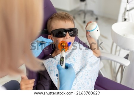 Dental clinic visit. Young positive boy patient showing thumbs up sign in dentist office.