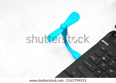 Flexible usb fan connected to a laptop on gray background with copy space. Staying cool when working at home.