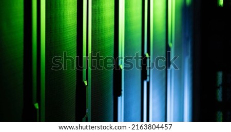 Image of close up of empty corridor with row of blue and green computer servers. global technology, data processing and connections concept.