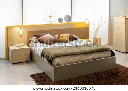 Interior of modern bedroom with soft bed and assorted abstract decorations illuminated with sunlight