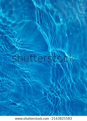 Defocus blurred transparent blue colored clear calm water surface texture with splashes and bubbles. Trendy abstract nature background. Water waves in sunlight.