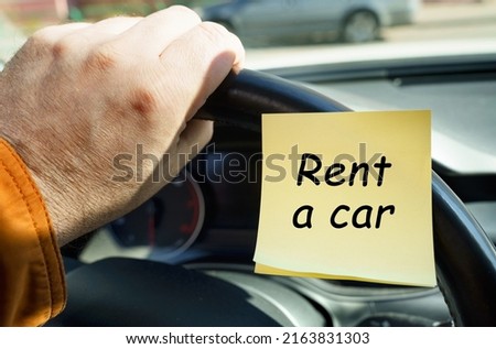 Business concept. A man holds on to the steering wheel, next to a sticker with the inscription - Rent a car