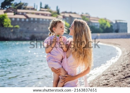 Mother and daughter tourists on background of beautiful view St. Stephen island, Sveti Stefan on the Budva Riviera, Budva, Montenegro. Travel to Montenegro concept