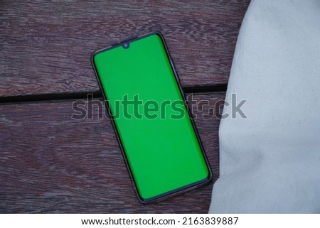 showing green screen phone on office table with bag next to it