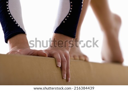 Female gymnast performing on balance beam, close-up, low section