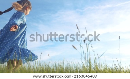 child girl dancing in the field park. happy childhood a family friendship concept. girl kid whirls in a blue dress in grass in the summer park. daughter in dancing whirls in the summer in nature sun