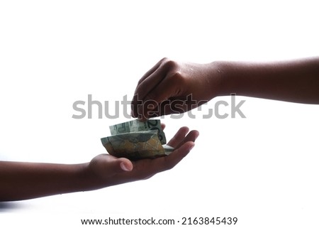 hand pose giving money.  Indonesian currency worth two thousand rupiah on a white background
