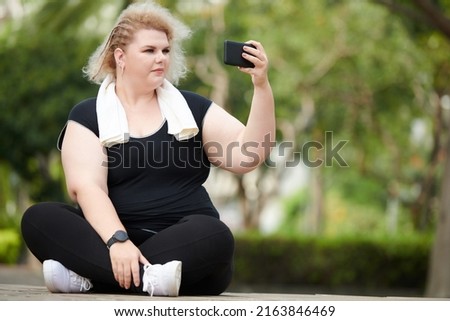 Plus size woman filming video for her blog after working out outdoors