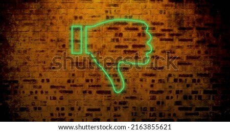 Image of glowing neon thumbs down icon on brick wall. social media and communication concept digitally generated image.