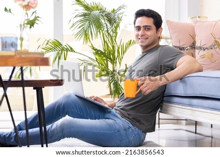 Happy young man working on laptop at home 