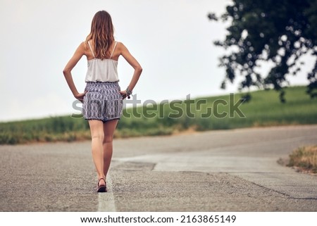 Young woman walking in the middle of a road.