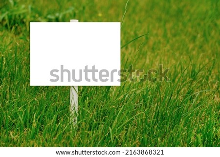 An empty signboard on a picturesque green lawn for your signature. horizontal photo, copy space
