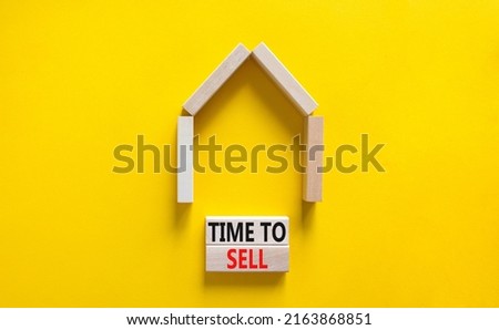 Time to sell house symbol. Concept words 'Time to sell' on wooden blocks near miniature house. Beautiful yellow background, copy space. Business and time to sell house concept.