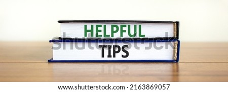 Helpful tips symbol. Books with words 'Helpful tips'. Beautiful wooden table, white background. Business and helpful tips concept. Copy space.