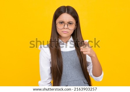 Serious teenager girl. Close-up portrait of her she nice cute attractive cheerful amazed girl pointing aside on copy space isolated on yellow background.