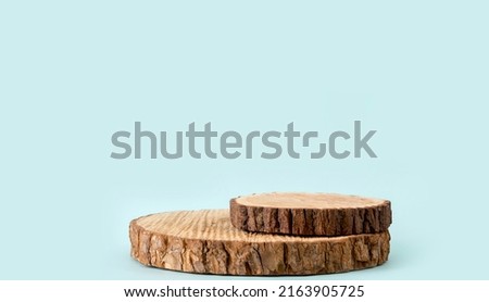 Two pine tree wood discs stacked as a podium for products, blue color background with lot of copy space, studio shot.