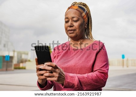 Mature african woman using mobile phone after sport workout in the city Royalty-Free Stock Photo #2163921987