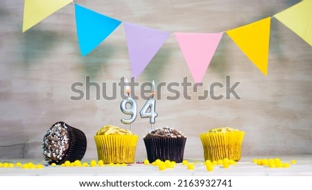 Birthday background with number 94. Beautiful birthday card with colorful garlands, a muffin with a candle burning copyspace