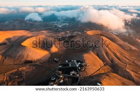 Volcanoes in Lanzarote at sunrise. Aerial view of Caldera Riscada. Canary Islands, Spain  Royalty-Free Stock Photo #2163950633