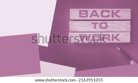 Words back to work written with wooden blocks on black background and luxury pen besides. Business concept.