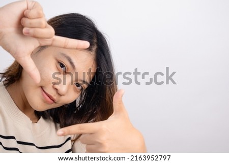 Portrait of an Asian woman posing with her fingers takes pictures on a white background.