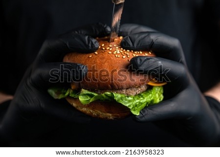 hamburger with cheese, cutlet, salad, tomato in hands.
