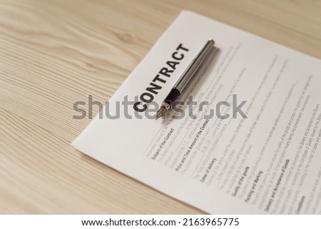 Contract lying at office on wooden table with copy space and silver pen for signature