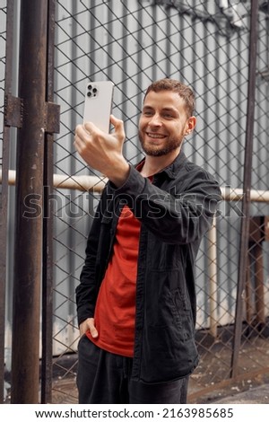 young man 25-35 with beard using smartphone selfie talking on video call