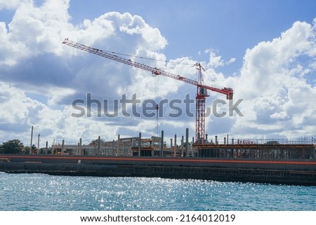 Construction of multi-storey buildings. Construction cranes on background blue sky. Modern high-rise buildings under construction. Construction on the beach.