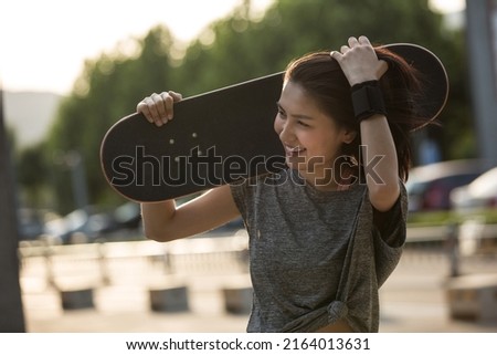 Young college girl walking happily after playing skateboarding - stock photo