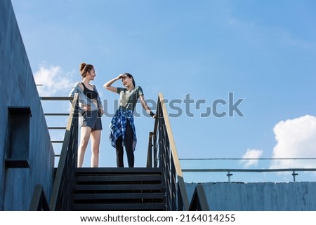 Two young woman exercising on urban buildings on a sunny summer day - stock photo