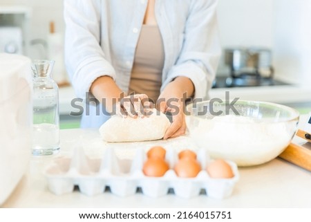 Kneading dough and making more gluten flexible, close-up of hands of housewife cooking in the kitchen - stock photo